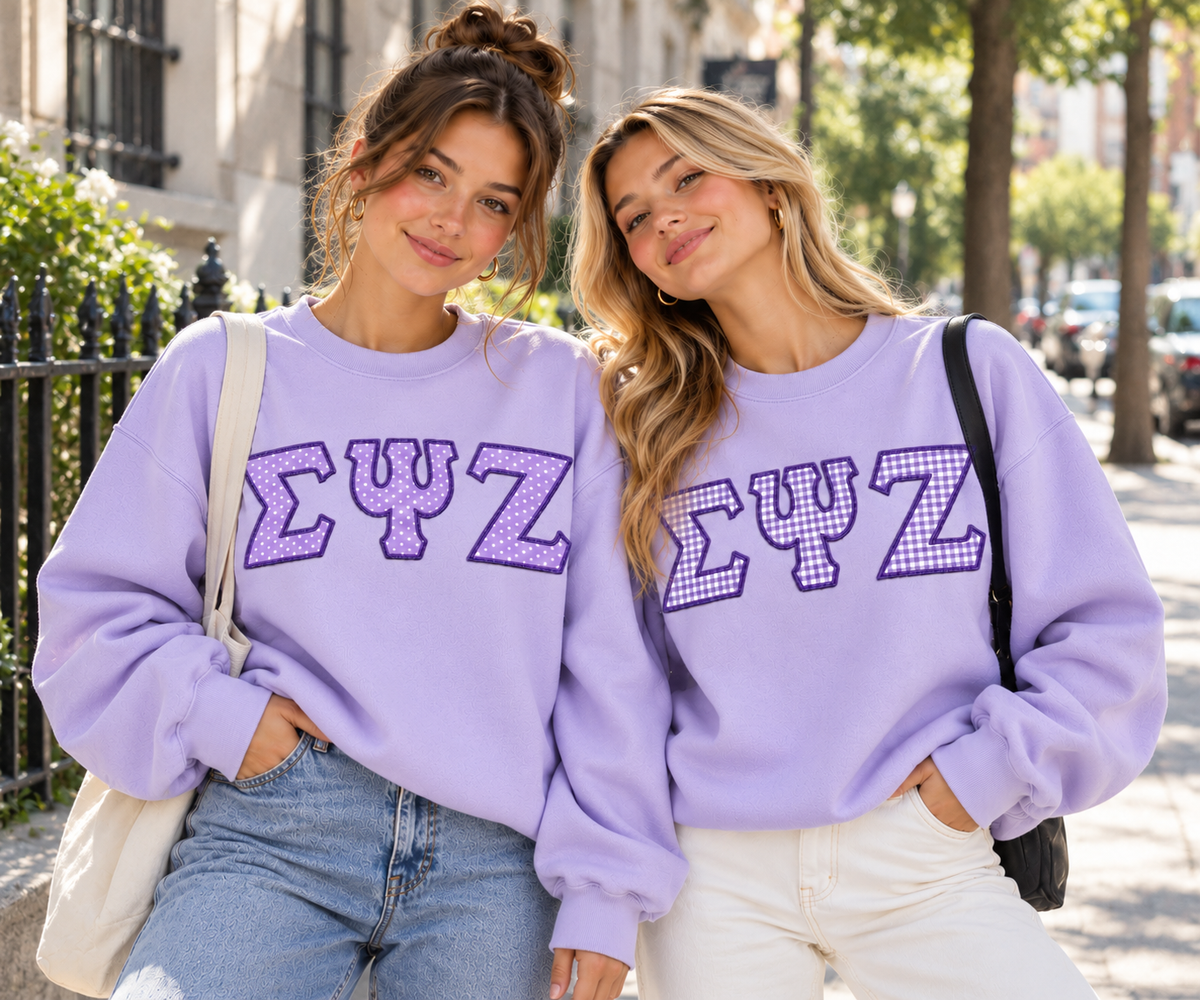 Two students wearing lavender sweatshirts with custom purple gingham appliqué Greek letters